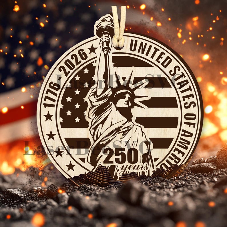 Może przedstawiać: Drewniana ozdoba z wizerunkiem Statuy Wolności, amerykańską flagą i napisem "United States of America 1776-2026 250 years". Ozdoba jest jasnobrązowa z beżowym sznurkiem do zawieszenia.