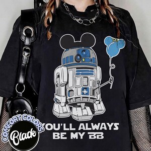 May include: Black t-shirt featuring a graphic of R2-D2 with Mickey Mouse ears and a blue balloon. The text "YOU'LL ALWAYS BE MY BB" is printed in white. The shirt has a Comfort Colors label.