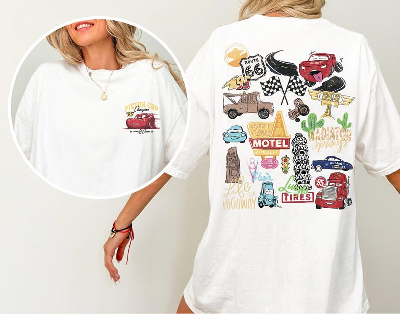 May include: White t-shirt featuring a graphic of a red race car with the text "Piston Cup '95 Champion" on the front. The back of the shirt has various cartoon car-themed illustrations, including Route 66 and checkered flags.