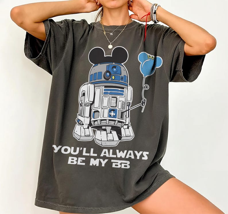 May include: Dark grey t-shirt featuring a cartoon R2-D2 character with Mickey Mouse ears holding a blue flower balloon. The text "YOU'LL ALWAYS BE MY BB" is printed in white below the graphic.