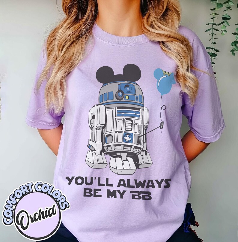 May include: A light purple Comfort Colors t-shirt featuring a graphic of R2-D2 with Mickey Mouse ears and a blue balloon. The text "YOU'LL ALWAYS BE MY BB" is printed below the graphic. A Comfort Colors Orchid logo is on the bottom left.