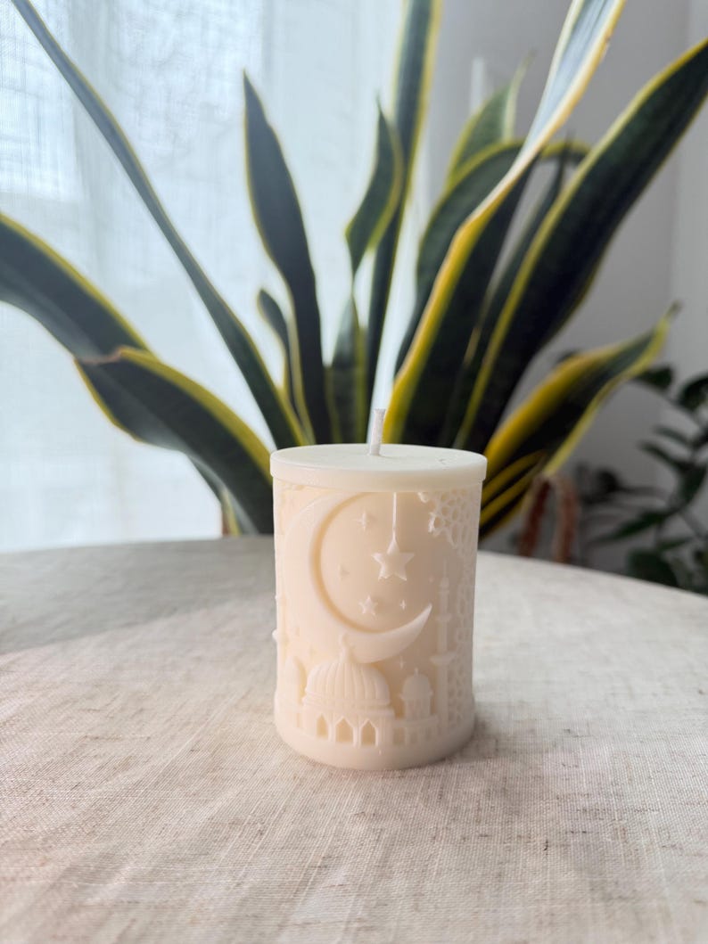 Puede incluir: Vela de pilar de color marfil con un dise&ntilde;o en relieve detallado. El dise&ntilde;o incluye una luna creciente, estrellas y elementos arquitect&oacute;nicos que se asemejan a mezquitas. La vela tiene una mecha central.
