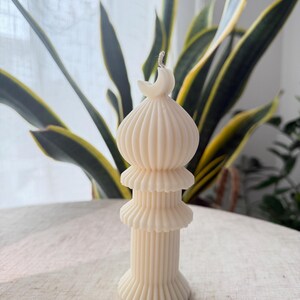 Puede incluir: Vela de color marfil con un dise&ntilde;o &uacute;nico. La vela presenta una estructura en capas con una luna creciente en la parte superior. La vela tiene una textura acanalada y mide aproximadamente 15 cm de altura. La vela no tiene perfume y es adecuada para la decoraci&oacute;n del hogar.