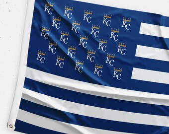 May include: A blue and white flag with a pattern of gold crowns and the letters "KC" repeated throughout. The flag is made of fabric and has a slightly wrinkled appearance.