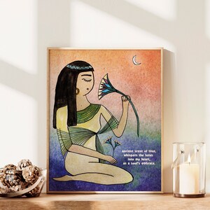 May include: A watercolor illustration of a woman with long black hair wearing a yellow and green dress. She is holding a blue and green lotus flower and looking at it. The background is a watercolor wash of orange, pink, and blue. The text "Ancient scent of blue, whispers the lotus into my heart, as a soul's embrace." is written in black at the bottom of the image.