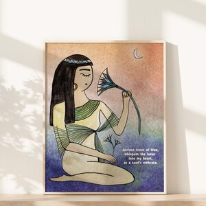 May include: A watercolor illustration of a woman with long black hair wearing a yellow and green dress. She is holding a blue lotus flower and looking at it. The background is a watercolor wash of orange, pink, and blue. The text "Ancient scent of blue, whispers the lotus into my heart, as a soul's embrace." is written in the bottom right corner.