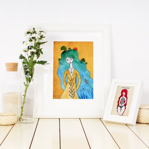 May include: Two framed watercolor illustrations of women with long hair. The first illustration features a woman with blue hair and a yellow dress, with trees growing from her hair. The second illustration features a woman with red hair and a blue swimsuit, with flowers growing from her body.