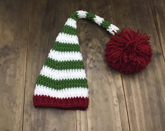 May include: Green and white striped crochet elf hat with a red pom-pom on top.