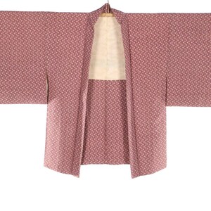 May include: A dusty rose kimono with a repeating floral pattern. The kimono is open, revealing a cream-colored lining. The sleeves are wide and the garment hangs from a wooden hanger. The fabric has a soft, textured appearance.