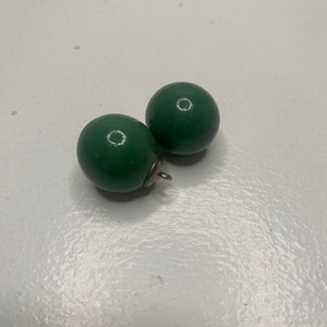 May include: Two green round wooden earrings with a silver hook.
