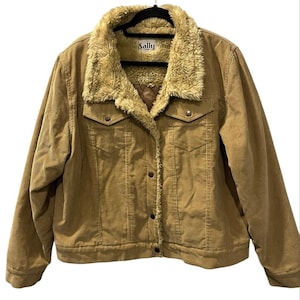 May include: A tan corduroy jacket featuring a beige faux fur collar and lining. The jacket has a button-front closure, two chest pockets with buttoned flaps, and a label at the inner neckline that reads Sally USA.