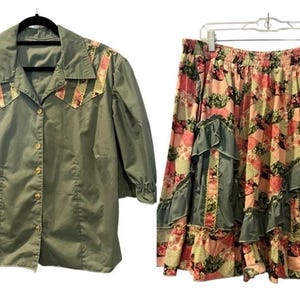 May include: A two-piece set consisting of a sage green button-down shirt with floral patterned shoulder yokes and three-quarter length sleeves, and a matching skirt featuring a patchwork floral print with sage green ruffled tiers and an elastic waist.