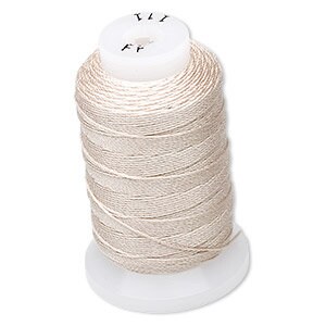 Op de afbeelding: Een spoel lichtbeige garen. De draad is strak gewikkeld rond een witte plastic spoel. De bovenkant van de spoel heeft kleine markeringen. De draad lijkt een fijn, glad materiaal te zijn, geschikt voor naai- of borduurprojecten.