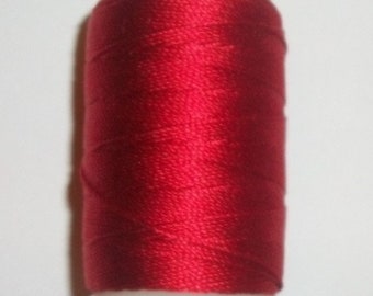 May include: A spool of bright red thread, tightly wound around a white plastic base. The thread has a glossy sheen, suggesting a smooth, possibly silk or satin, texture. Ideal for sewing, embroidery, or crafting projects.
