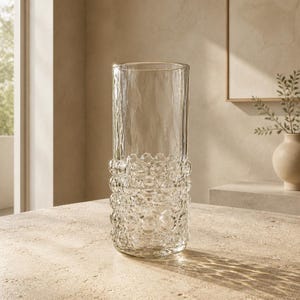 May include: A tall, cylindrical clear glass vase featuring a smooth upper section and a textured lower portion adorned with a repeating pattern of raised, rounded glass bubbles that create a tactile, multi-dimensional surface appearance.