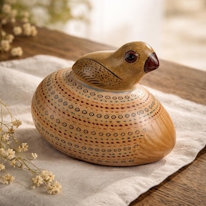 May include: A handcrafted ceramic bird figurine with a rounded body and a small head. The bird is painted in shades of brown and beige, with intricate dot and line patterns. The beak is a deep red, and the eyes are dark brown.