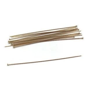 May include: A close-up of a pile of gold-colored head pins, with one pin extending out to the right.