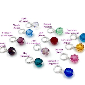 May include: Twelve silver charms with coloured glass beads, each representing a different month of the year. The charms are labelled with the month and the corresponding birthstone.