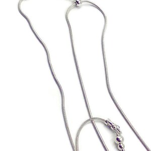 May include: A silver chain necklace with a magnetic clasp and a small silver bead at the end. The chain is made of a snake chain style.