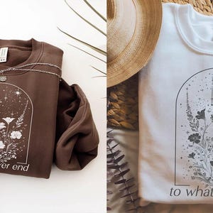 May include: Two sweatshirts with a floral design and the text "to whatever end". One sweatshirt is brown with white flowers and the other is white with black flowers.