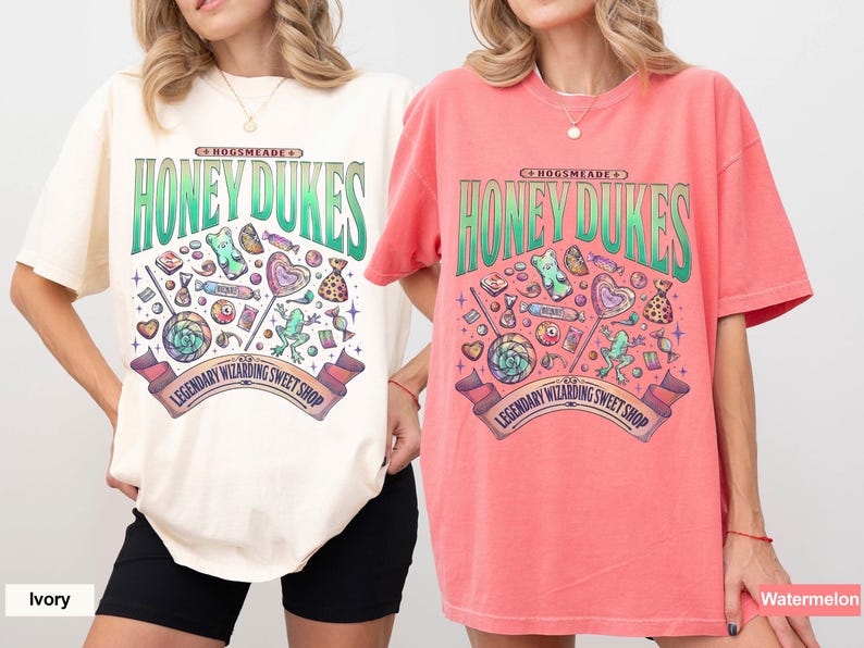 Może przedstawiać: Dwie koszulki, jedna w kolorze kości słoniowej, druga w kolorze arbuza, z logo Honeydukes. Projekt zawiera ilustracje cukierk&oacute;w i napis "Legendary Wizarding Sweet Shop". Koszulki mają kr&oacute;tkie rękawy i luźny kr&oacute;j.