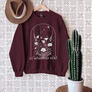 May include: Burgundy sweatshirt with a white floral design and the text "to whatever end" printed on the front.