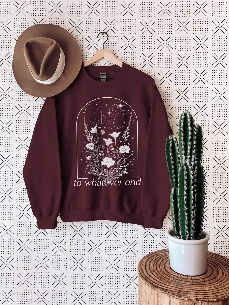 May include: Burgundy sweatshirt with a white floral design and the text "to whatever end" printed on the front.