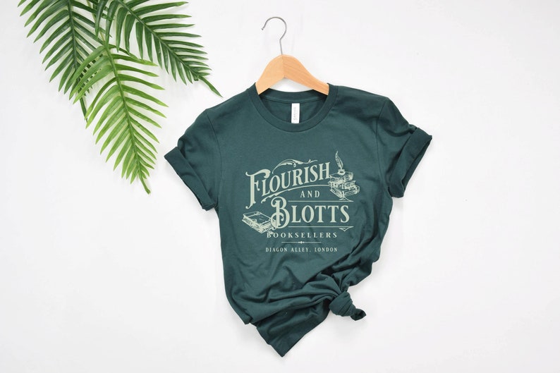 May include: A dark green t-shirt with a white graphic print of the text "Flourish and Blotts Booksellers Diagon Alley, London".
