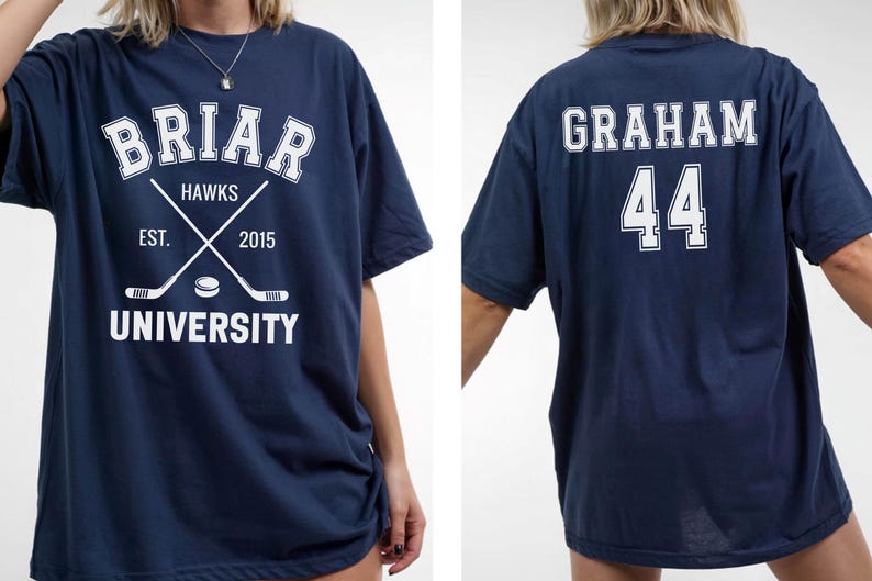 May include: Navy blue t-shirt with white text and graphics. The front features "Briar Hawks University" with crossed hockey sticks and a puck. The back displays "Graham 44". A casual, oversized tee.