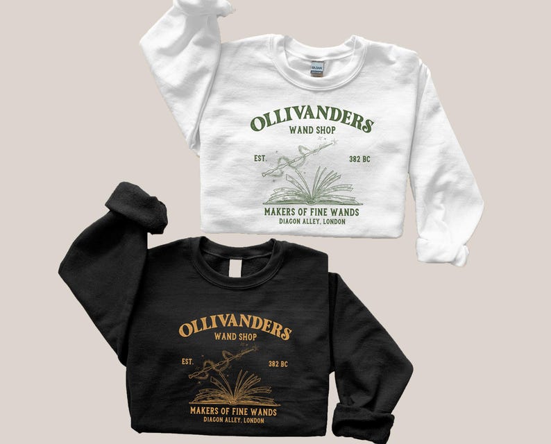 May include: Two black and white sweatshirts with a green graphic design of a wand and book. The text on the graphic reads "Ollivanders Wand Shop Est. 382 BC Makers of Fine Wands Diagon Alley, London."