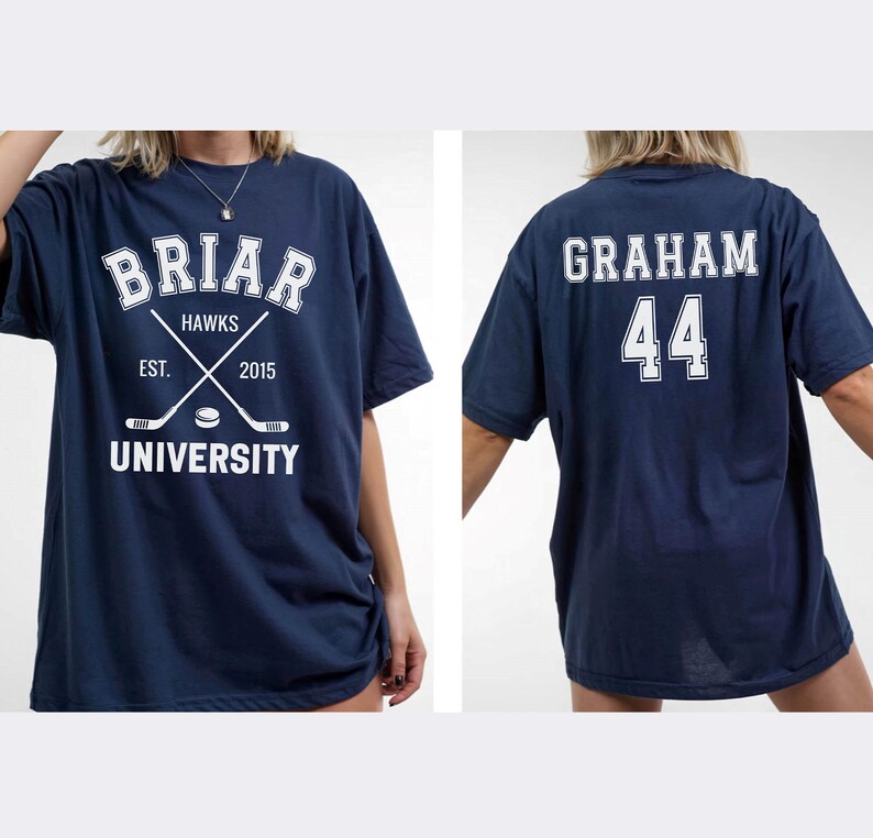 May include: Navy blue t-shirt with white text and graphics. The front features "Briar Hawks University" with crossed hockey sticks and the year "2015." The back displays "Graham 44." A casual, oversized fit.