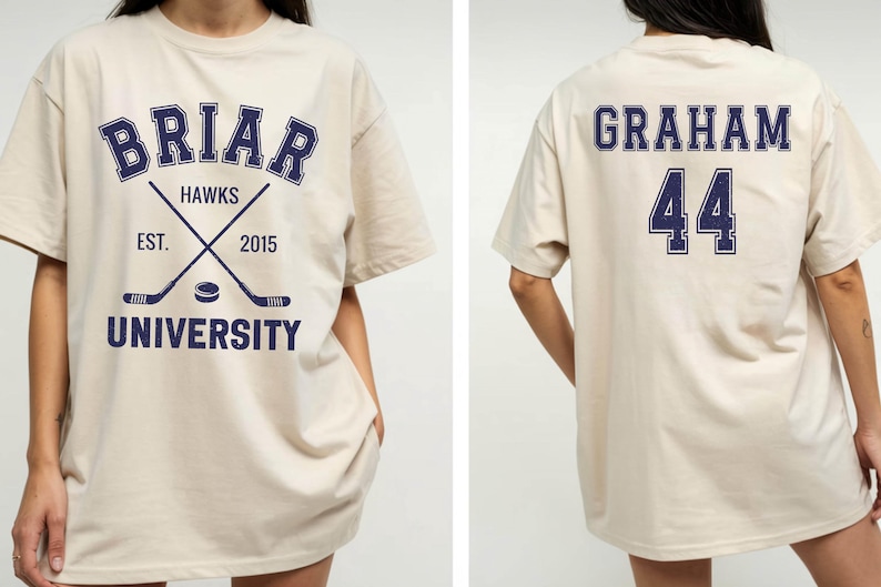 May include: Beige t-shirt with navy blue text and graphics. The front features "Briar Hawks University" with crossed hockey sticks and a puck. The back displays "Graham 44". A casual, oversized fit.