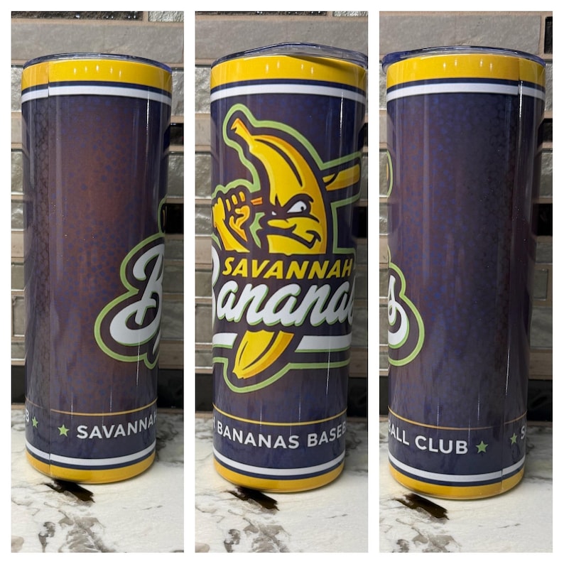 Puede incluir: Un vaso de acero inoxidable con un fondo azul marino y el logotipo amarillo y verde del equipo de b&eacute;isbol Savannah Bananas. El vaso tiene un borde amarillo y las palabras "Savannah Bananas Baseball Club" est&aacute;n impresas en la parte inferior.