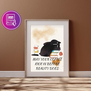 Può includere: Stampa artistica incorniciata con un gatto nero che dorme sui libri, con una pila di tazze da caffè colorate. La stampa include il testo "MAY YOUR COFFEE KICK IN BEFORE REALITY DOES" in bianco. L'opera d'arte è esposta su una parete marrone.