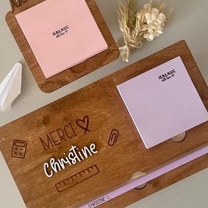 Peut inclure: Organisateur de bureau en bois avec un bloc-notes adhésif rose, un crayon violet et le texte "MERCI Christine" gravé sur la surface. L'organisateur a également une petite calculatrice, une règle et une agrafeuse gravées sur la surface.