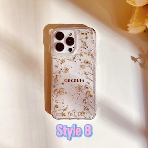 May include: A clear phone case with a floral design and gold glitter. The case has the name "Cecelia" written on it. Style 8.