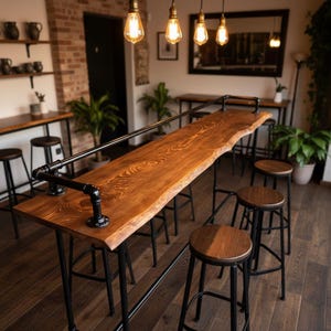 May include: A long, live-edge wooden bar table with a dark stain, supported by black metal legs and a foot rail. The table is surrounded by matching bar stools with wooden seats and black metal frames. Overhead, Edison-style light bulbs hang from the ceiling.