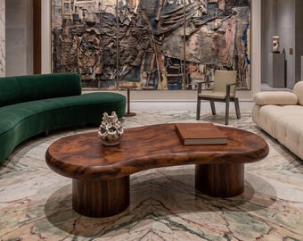 Mesa de centro escultural de nogal en madera maciza con diseño ovalado orgánico.
