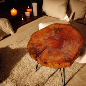 Pode incluir: Uma mesa redonda de madeira com acabamento em madeira natural e pernas de cabelo preto. O tampo da mesa tem um padrão de grão de madeira único.