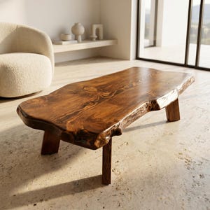 Può includere: Un tavolino basso realizzato con un'unica lastra di legno marrone scuro con bordo naturale. La superficie presenta venature del legno e nodi pronunciati. Il tavolo è sostenuto da quattro robuste gambe in legno dritte della stessa finitura.