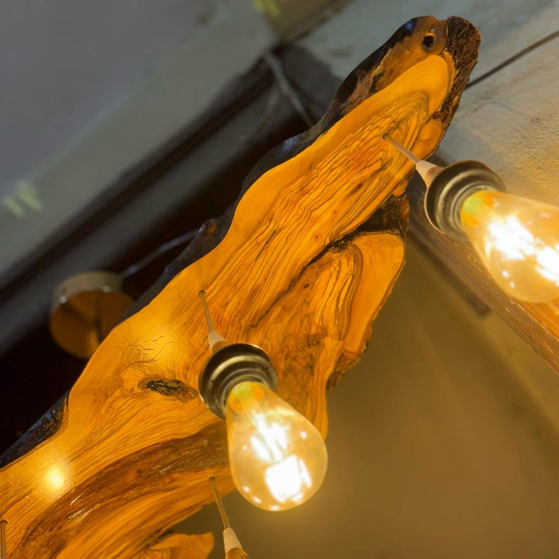 May include: A rustic wooden light fixture with three Edison bulbs hanging from a natural wood branch. The wood has a rich, warm brown color with a natural grain pattern.