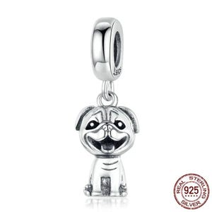 May include: A silver charm featuring a smiling pug dog design. The charm is made of 925 silver and has a loop at the top for attaching to a bracelet or necklace. The charm is detailed with the dog's facial features and body.