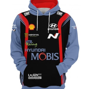 Puede incluir: Una sudadera con capucha azul y negra con el logotipo de Hyundai Motorsport, el logotipo de Monster Energy y el texto "Hyundai Mobis".