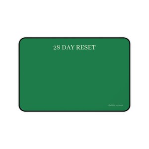 May include: A rectangular green mousepad with rounded corners. The text "28 DAY RESET" is centered at the top, with "discipline over mood" in smaller text at the bottom. The mousepad has a black border.