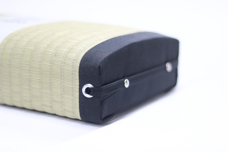 Angled front view of the Agura Tatami cushion.
The cushion’s sides are covered with black edge fabric, and a sturdy handle is securely stitched in place. Its practical design makes it easy to carry and store, while the precise craftsmanship is evident in every detail.