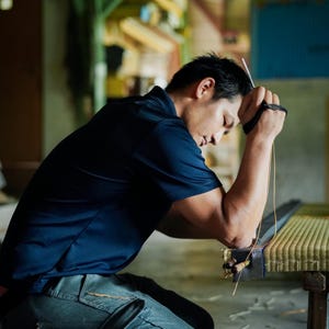 Ryuji Koyanagi, the fifth-generation craftsman of Koyanagi Tatami, a traditional tatami shop with over 150 years of history, is seen meticulously finishing a tatami mat in his workshop. With a sharp, focused gaze, he hand-stitches the mat’s edge, embodying the deep pride and sincere dedication that define Japanese craftsmanship.