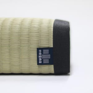 Rear view of the Agura Tatami cushion.
A brand tag from Koyanagi Tatami Shop, a heritage maker with over 150 years of history, is carefully sewn onto the black edge of the cushion—symbolizing both trust in craftsmanship and authentic Japanese quality. The meticulous attention to detail reflects a refined finish that combines the aesthetic of traditional Japanese design with everyday functionality.