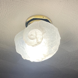 May include: A white, textured glass ceiling light fixture with a gold metal base.