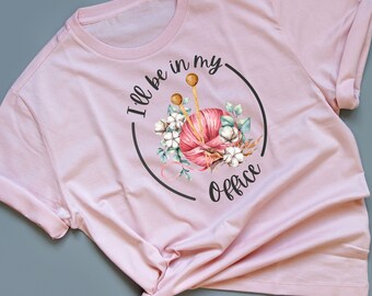May include: Pink t-shirt with a graphic of a ball of yarn, knitting needles, and flowers. The text "I'll be in my office" is written around the graphic.