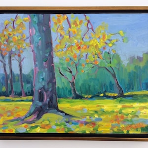 Puede incluir: Una pintura al &oacute;leo de un paisaje con &aacute;rboles de hojas amarillas y naranjas, sobre un fondo de follaje verde y cielo azul. La obra de arte est&aacute; enmarcada en un marco dorado con un borde interior negro, creando una pieza vibrante y colorida.